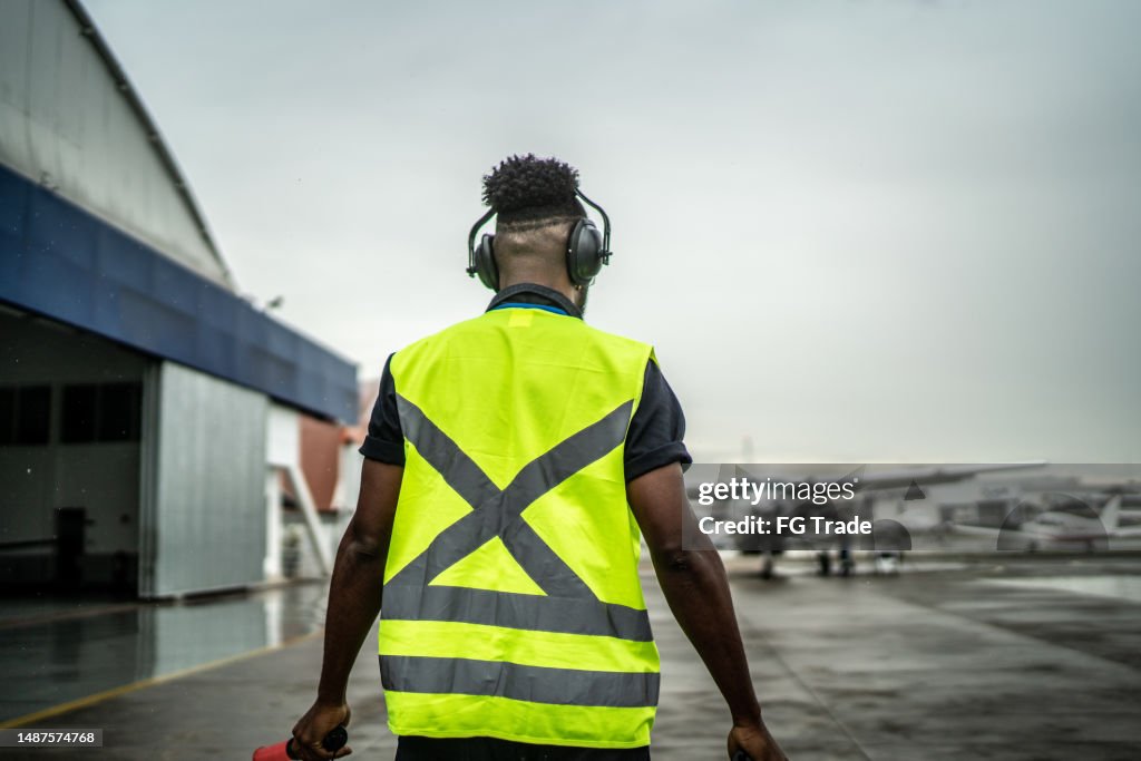 Man signaling the pilot with marshalling wands on airport