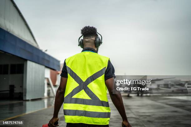 man signaling the pilot with marshalling wands on airport - waistcoat stock pictures, royalty-free photos & images