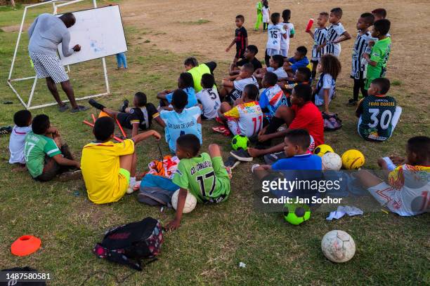 Football coach draws game tactics on a board while young Afro-Colombian players watch during a training session on November 24, 2022 in Necoclí,...