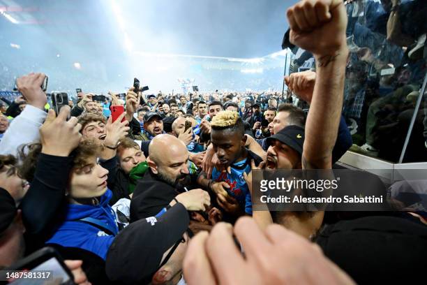 Victor Osimhen of SSC Napoli is surrounded by SSC Napoli fans after their side wins the Seria A title after the Serie A match between Udinese Calcio...