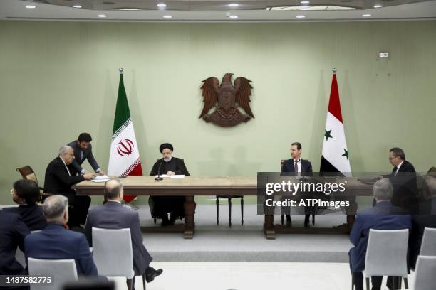 Syria's President Bashar al-Assad, and Iranian counterpart Ebrahim Raisi exchange documents after signing a memoranda of understanding on "long-term...