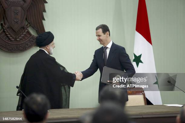 Syria's President Bashar al-Assad, and Iranian counterpart Ebrahim Raisi exchange documents after signing a memoranda of understanding on "long-term...