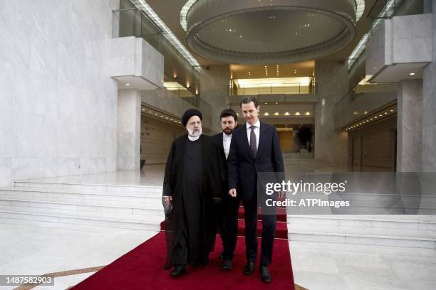 Syria's President Bashar al-Assad, and Iranian counterpart Ebrahim Raisi exchange documents after signing a memoranda of understanding on "long-term...