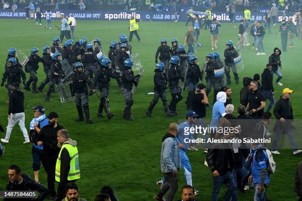 Police and SSC Napoli fans are seen on the pitch after their side wins the Seria A title after the Serie A match between Udinese Calcio and SSC...
