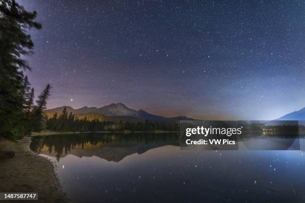 The constellation of Ursa Major, the Great Bear, and the asterism of the Big Dipper low in the north over Lake Edith in Jasper National Park, on a...