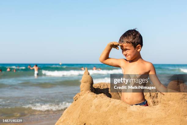 junge baut eine sandburg am strand - kind sandburg stock-fotos und bilder