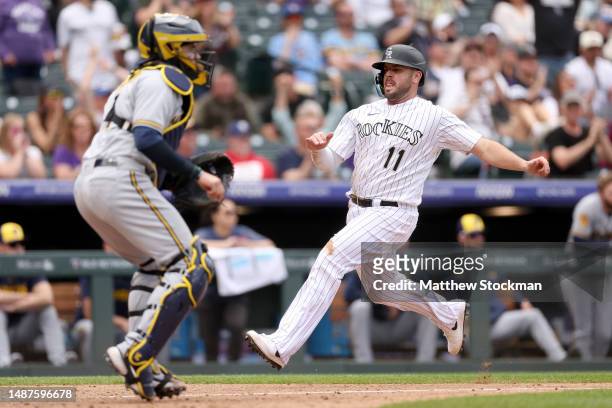 Mike Moustakas of the Colorado Rockies scores on a Harold Castro 2 RBI single against the Milwaukee Brewers in the eighth inning at Coors Field on...
