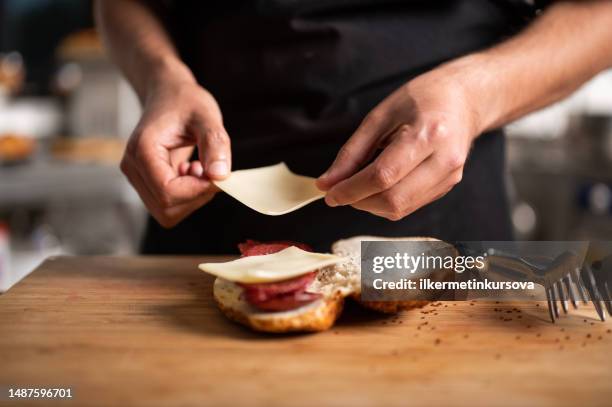 a male chef prepares a sausage and cheese sandwich - sandwich bildbanksfoton och bilder