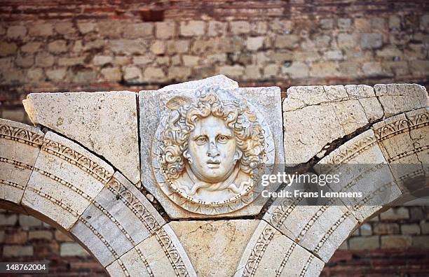 sculpture of face on roman ruins, leptis magna. - ruins of leptis magna stock pictures, royalty-free photos & images