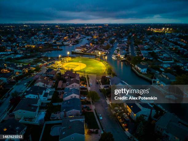 illuminated public community baseball stadium in oceanside, long island on sunset dark skyline, twilight. aerial view - baseball game stadium stock pictures, royalty-free photos & images