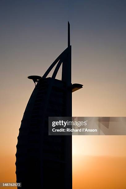 burj al arab silhouetted at sunset. - national landmark stock pictures, royalty-free photos & images