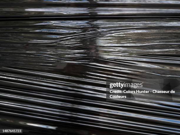 stretched and wrinkled black plastic on which daylight is reflected in paris, france - vinyl film stock pictures, royalty-free photos & images