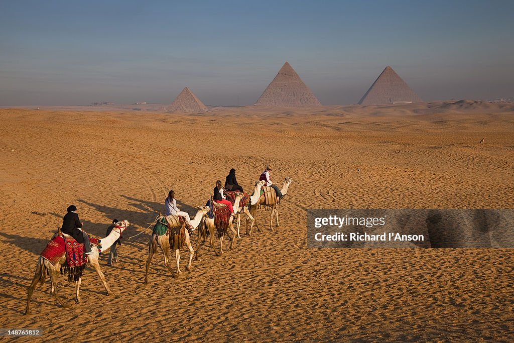 Tourists on camels & Pyramids of Giza.