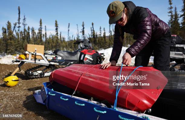 SnowEx campaign member master's student Sage Ebel packs science equipment to be hauled by a snowmobile for snow measurements in a boreal forest...