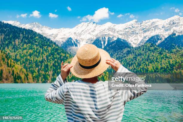 woman admires the picturesque mountain lake, rear view. lake ritsa, abkhazia. - abkhazia stock pictures, royalty-free photos & images