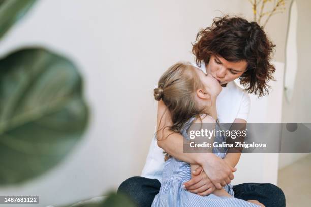 young mother and daughter having fun in bedroom at home - free kisses photos et images de collection