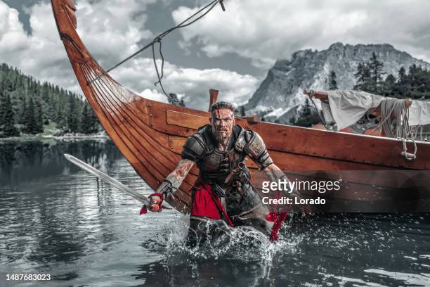 viking warrior sailing on a fjord on an authentic viking long boat - ancient vikings stockfoto's en -beelden