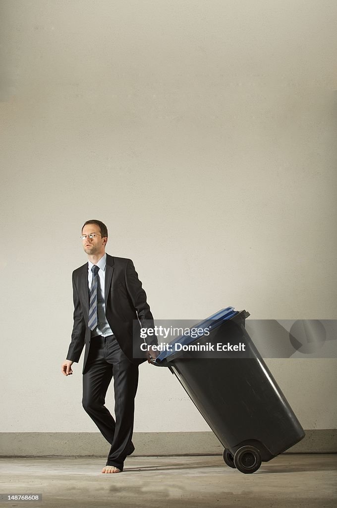 Barefoot businessman with trash can