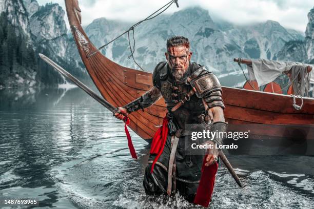 viking warrior sailing on a fjord on an authentic viking long boat - ancient vikings stockfoto's en -beelden