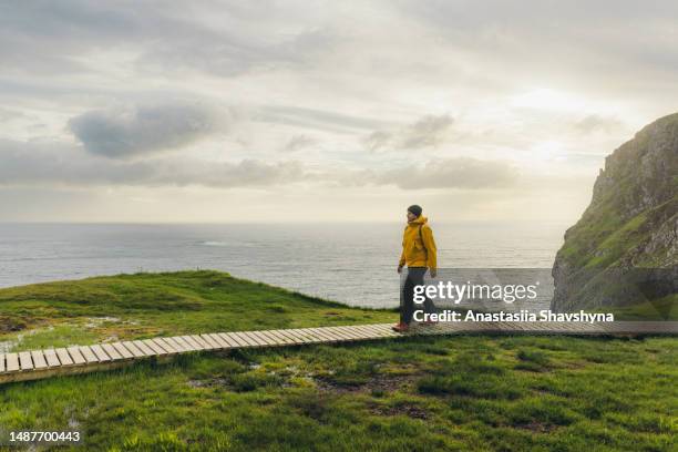 man backpacker hiking on footpath on scenic runde island with ocean view in norway - cliff side stock pictures, royalty-free photos & images