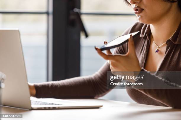 junge frau benutzt laptop und telefoniert über die freisprecheinrichtung - übersetzung stock-fotos und bilder