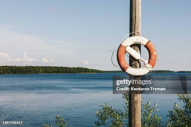 a lifebuoy on a post by a lake. - rettungsring stock-fotos und bilder