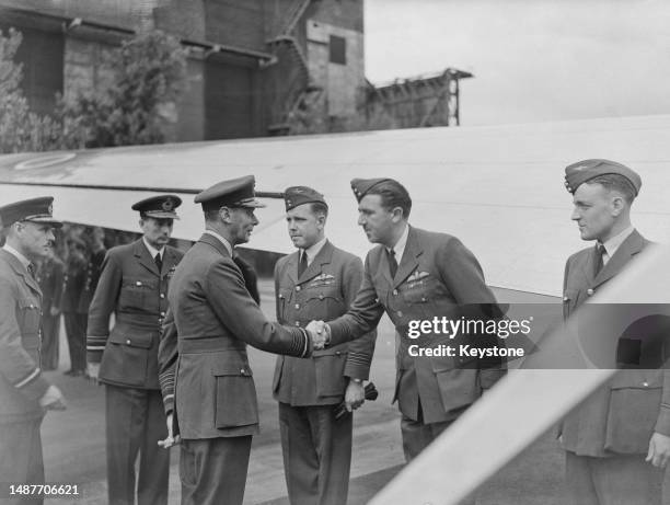 King George shakes hands with a crew member before boarding a flight to Northern Ireland at an unidentified airfield, 17th July 1945. He is...