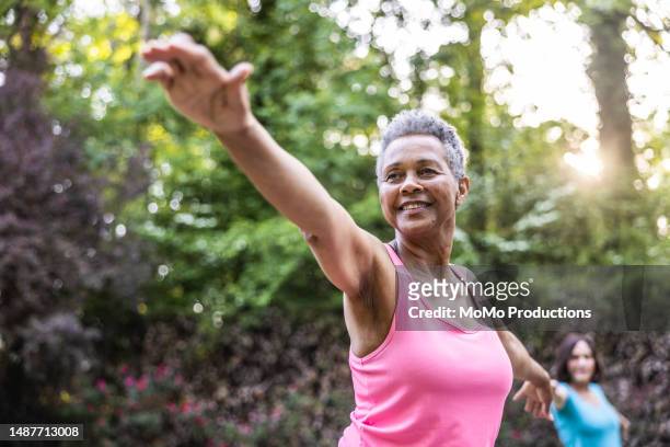 senior women taking a yoga class in beautiful garden - seniors exercising stock pictures, royalty-free photos & images