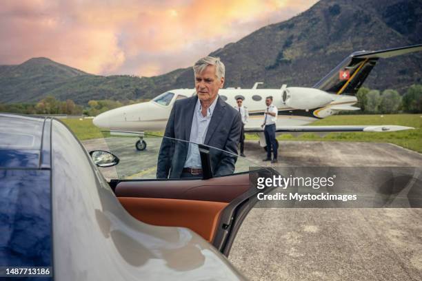 chauffeur opening luxury car door, private jet in the background - open land stock pictures, royalty-free photos & images
