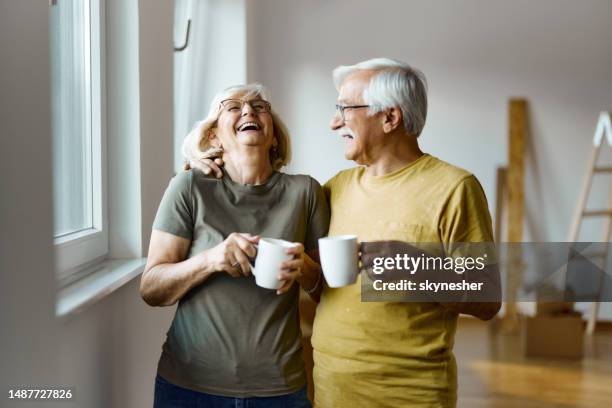 cheerful mature couple having fun by the window at their new home. - tea cup stock pictures, royalty-free photos & images