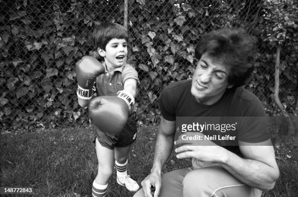 Portrait of actor Sylvester Stallone with 6-year-old son Sage Stallone wearing boxing gloves during photo shoot in their yard. Pacific Palisades, CA...