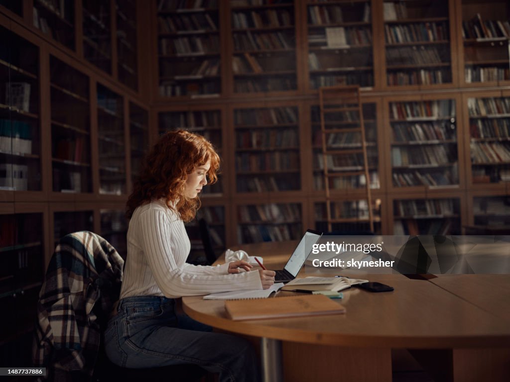 Studentin macht sich Notizen beim E-Learning in der Bibliothek.