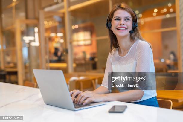 beautiful mixed caucasian female customer service support staff working from a workspace with cafe - customer experience stock pictures, royalty-free photos & images