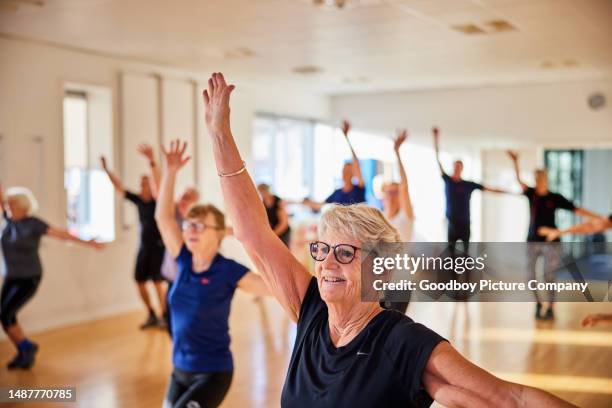 mujer mayor sonriente y otras personas que toman una clase de ejercicios en el gimnasio - exercise class fotografías e imágenes de stock