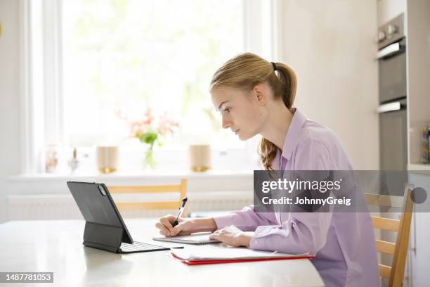 adolescente haciendo la tarea en la mesa de la cocina - intensidad del color fotografías e imágenes de stock