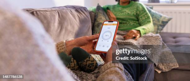 adjusting the central heating on the mobile app - thermostaat stockfoto's en -beelden