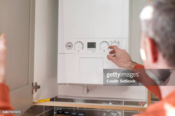 adjusting the boiler at home - caldeira imagens e fotografias de stock