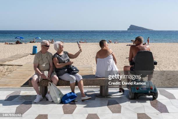 Couple of British tourists take a selfie with her mobile phone in Levante beach promenade on May 05, 2023 in Benidorm, Spain. On May 6 King Charles...