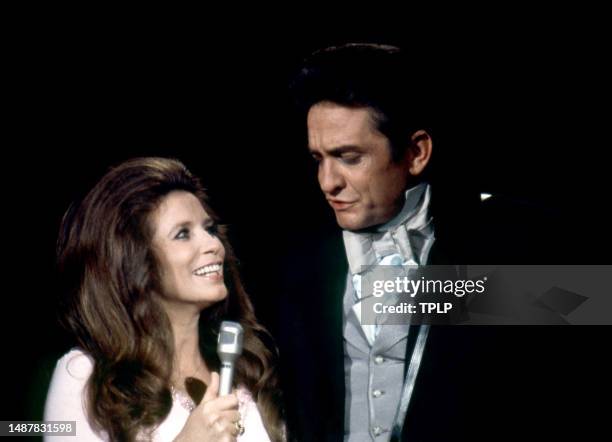 American singer, songwriter and dancer June Carter Cash and her husband, Country singer Johnny Cash sing on stage during an episode of The Johnny...