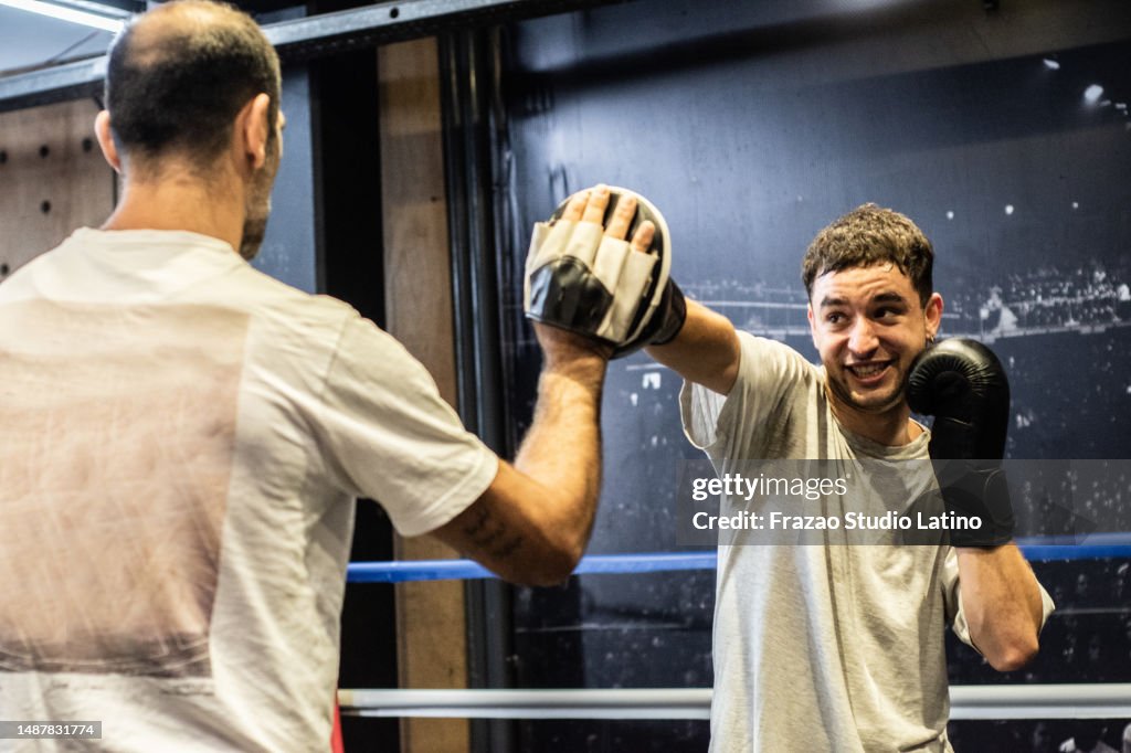 Young man training boxing with his trainer in the ring