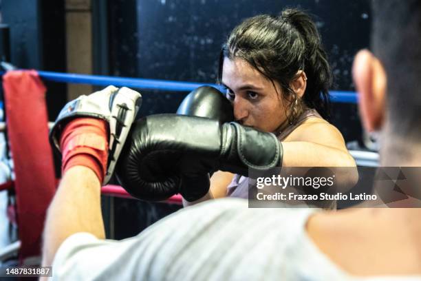 young woman training boxing with her trainer in the ring - female boxer stock pictures, royalty-free photos & images