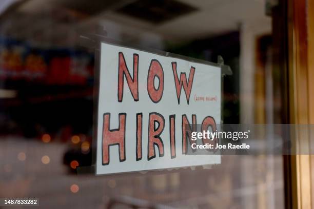 Now Hiring' sign posted on the window of a business looking to hire workers on May 05, 2023 in Miami, Florida. A report by the Bureau of Labor...