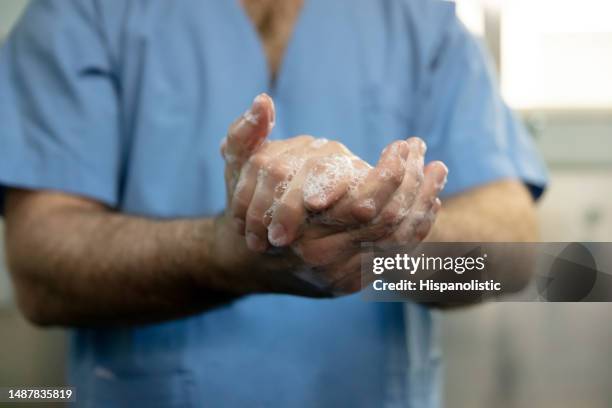 close up of unrecognizable male surgeon washing his hands scrubbing up before surgery - nurse washing hands stock pictures, royalty-free photos & images