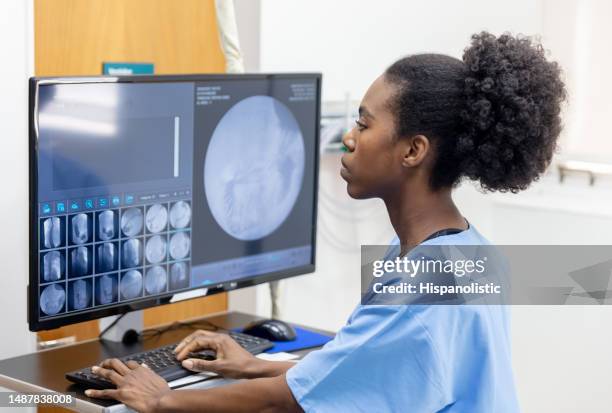 radiologista afro-americana focada olhando para os exames de um paciente para escrever o relatório na clínica - ultrasonografia médica equipamento de monitoramento - fotografias e filmes do acervo