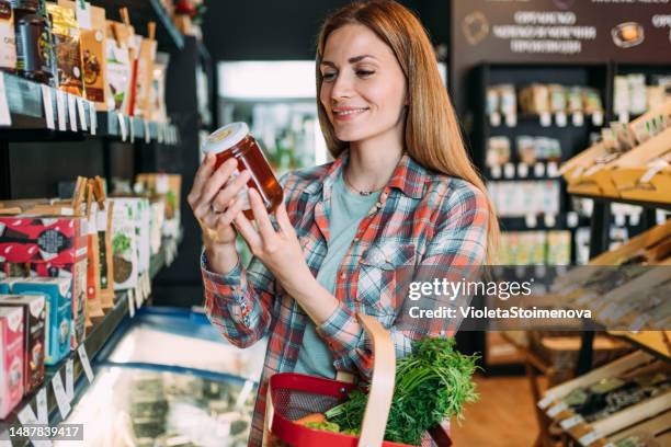 woman shopping at an organic market and looking at ingredients. - honey stockfoto's en -beelden