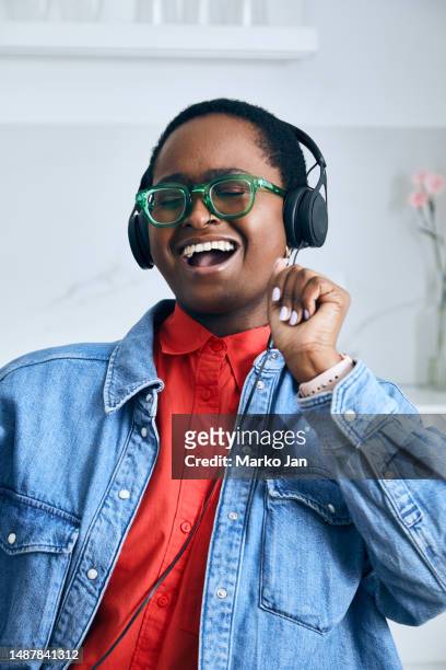 beautiful black girl with headphones, enjoying music from the smart phone - mp3 juices 個照片及圖片檔