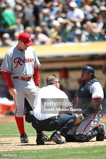 Manager Eric Wedge of the Seattle Mariners and medical personal check on Miguel Olivo after taking a ball off his groin during the game against the...