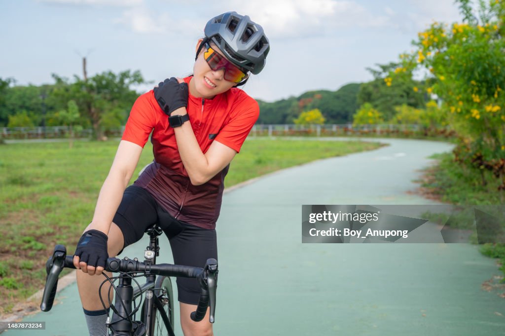 Asian female cyclist having shoulder pain from riding a bike long time.