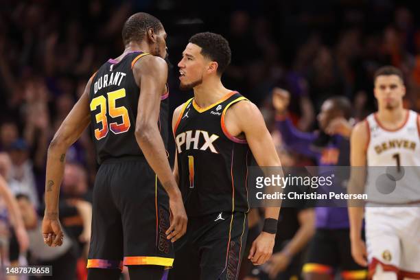 Devin Booker of the Phoenix Suns celebrates with Kevin Durant after a three-point shot against the Denver Nuggets during the first half of Game Three...
