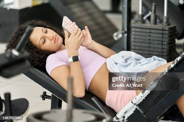 young woman using phone while having exercise break in gym - gym resting stock pictures, royalty-free photos & images